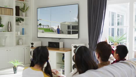 행복 한 가족 이 집 에서 함께 앉아서 tv 에서 육상 하이 점프 대회 를 시청 하고 있다