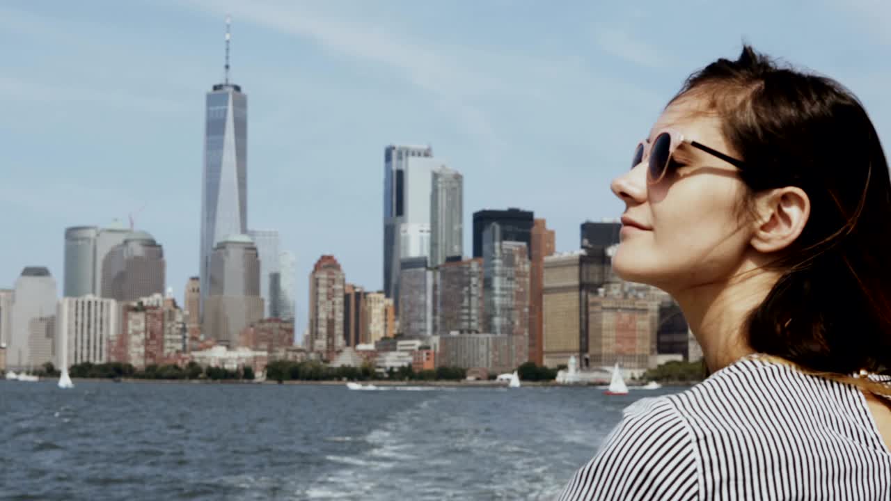 una joven feliz va en barco a través del east river en nueva york, estados unidos, mirando a manhattan y disfrutando