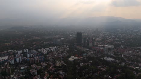 aerial tour of southern mexico city during sunset with sunbeams breaking through clouds