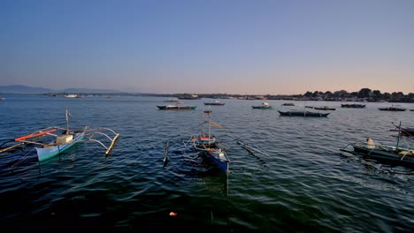 a pervasive blue hue around small fishing boats moored at the shore of puerto princesa city, capital of palawan, philippines