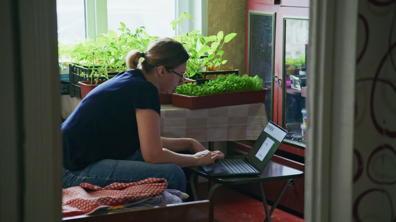 Woman working from home, surrounded by potted plants
