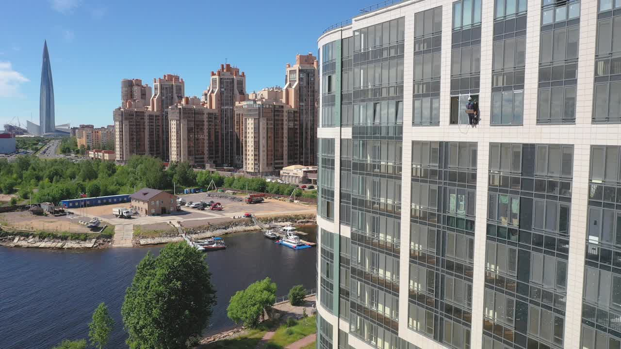 러시아 상트페테르부르크의 배경에 오코노미야키 구조가 있는 건물 창문 청소부의 공중 드론 정적 샷