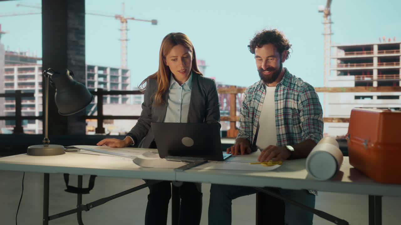 Two Engineers or Architects Reviewing Plans at a Construction Site Office