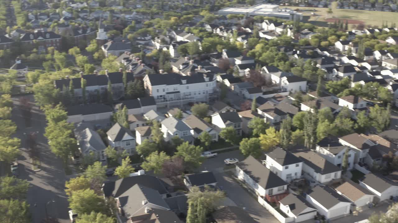 summer sunrise arial panaramic parallel fly over Calgary suburb of Inverness town of McKenzie Highands residential community of low rise detauched homes next to freeway by school field AB CAN