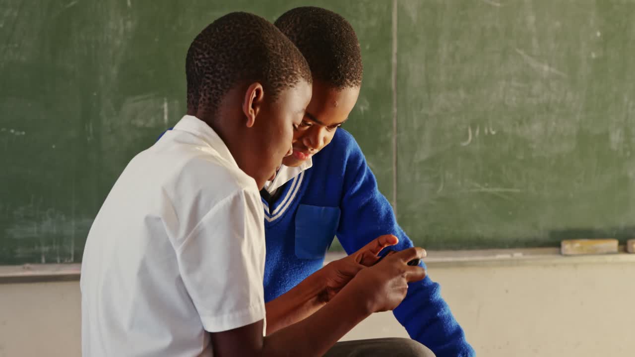 Alunni che usano uno smartphone durante la ricreazione in una scuola di una township 4k