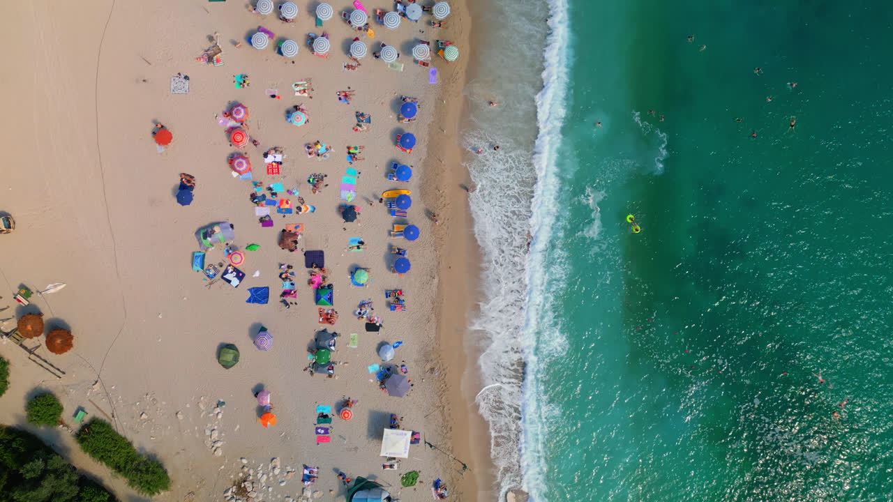 drone aéreo de arriba hacia abajo disparado sobre olas de agua de mar de color turquesa que se estrellan a lo largo de la playa de gjipe en albania en un día soleado