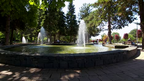 Springbrunnen-Im-Stadtpark-Kühlen-An-Einem-Heißen-Sommertag-Die-Atmosphäre-Im-Park-Ab,-Der-Von-älteren-Menschen-Und-Kindern-Besucht-Wird