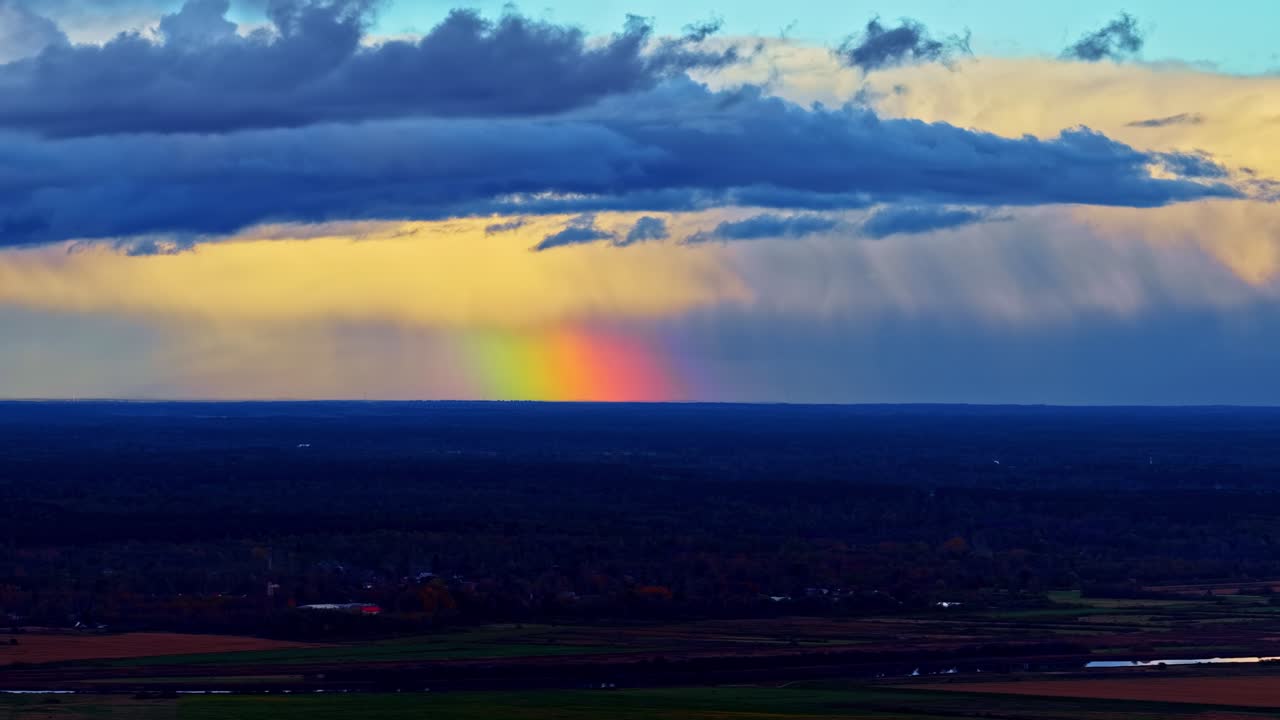Aerial drone view of sunset over distant hills with soft light cascading through layered rain clouds, cinematic shot