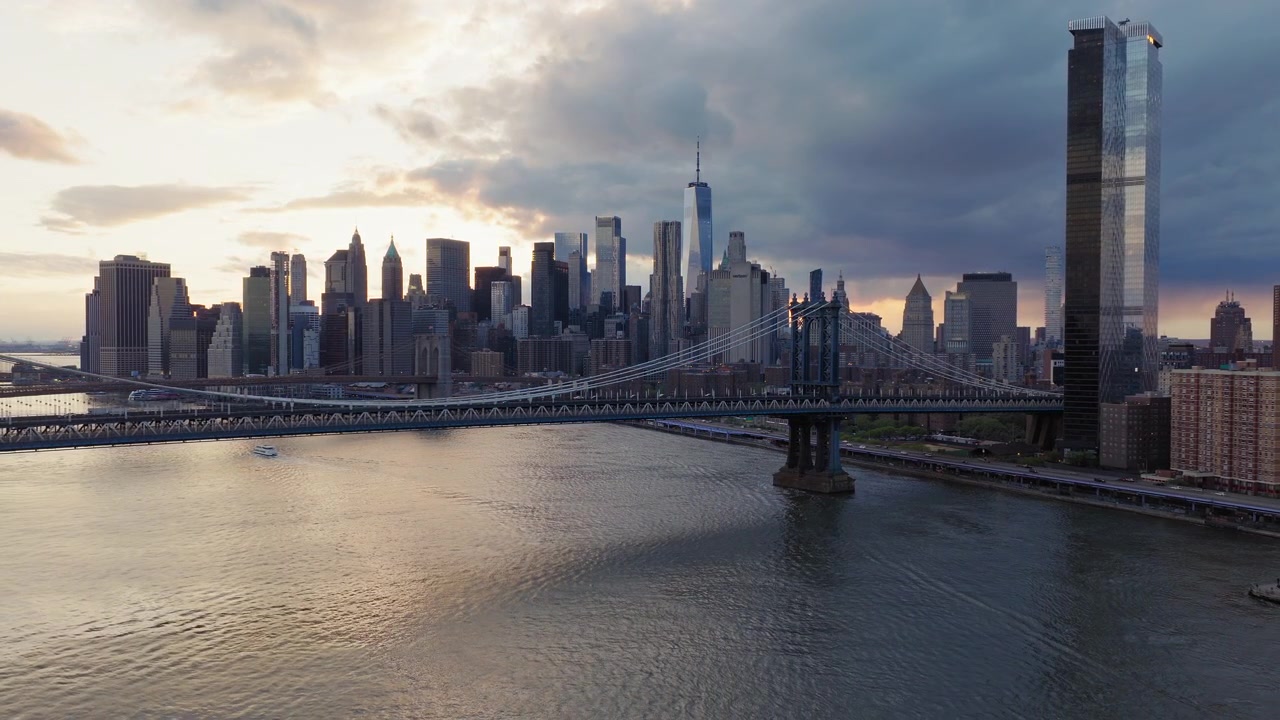 Panorama aereo con drone del Ponte di Brooklyn al tramonto, NYC. Skyline di Manhattan e One World Trade Center sullo sfondo. Nuvole dense