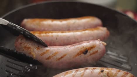 persona de la cosecha girando salchichas caseras fritando en sartén