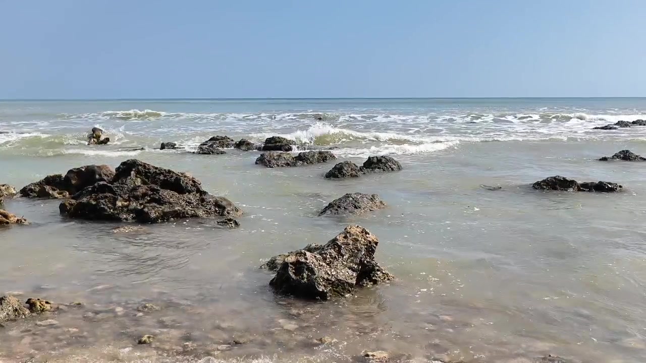 Onde Delicate che si Infrangono su una Costa Rocciosa in una Giornata di Sole