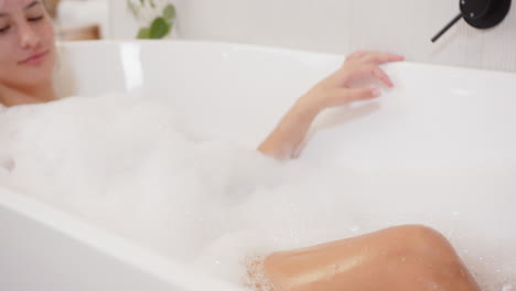 Relaxing in bathtub, woman enjoying bubble bath and listening to music