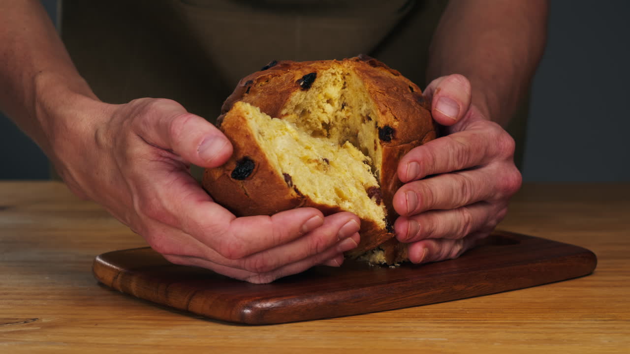 Traditional English Christmas cake tied with a jute thread on the black background. Italian classic Panettone .Pastry Chef sprinkles powdered sugar through a sieve on the fruit Easter cake with raisins. High quality 4k footage