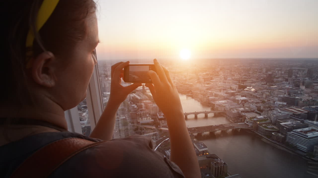 Turista che scatta una fotografia del tramonto nello skyline di Londra, vista da The Shard.