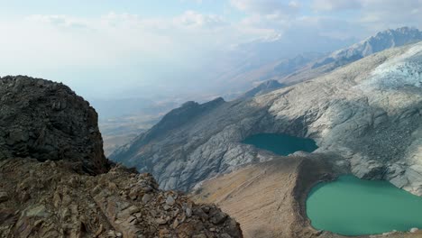 rocky terrain, glacier slopes, and twin turquoise lakes of paso del zorro in the high andes of peru - dramatic aerial parallax