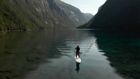 stand up paddleboarding on a serene lake surrounded by mountains