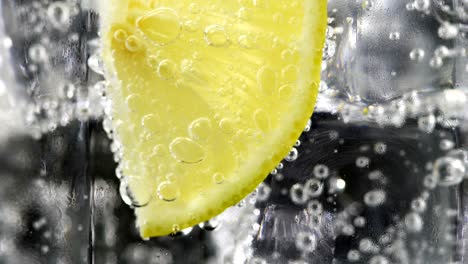 macro close up slice lemon, ice cubes and bubble float soda water.