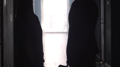 silhouettes of office workers shaking hands and walking along hallway