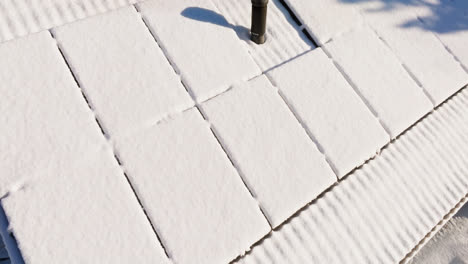 aerial close-up around snow covered solar panels on a house roof, winter day