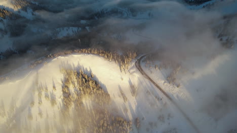 aerial view of teton pass wyoming on sunny winter morning, snow capped hills, road and light clouds