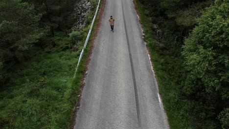 Toma-Aérea-De-Arriba-Hacia-Abajo-De-Una-Persona-Caminando-Por-La-Calle-En-El-Paisaje-Forestal-De-Noruega