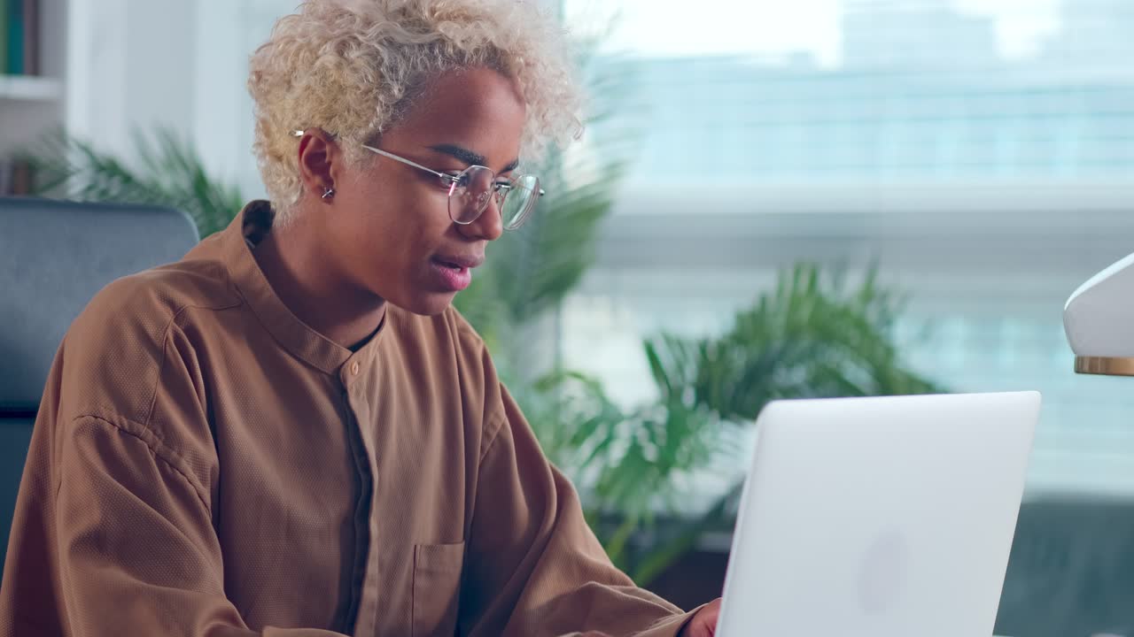Junge afroamerikanische Freiberuflerin arbeitet am Laptop und erledigt eine Aufgabe.