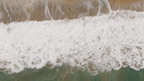 Vista-Aérea-De-Las-Olas-Del-Océano-De-Espuma-Rompiendo-En-La-Playa