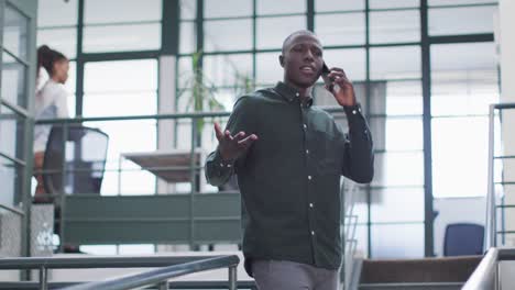 Happy-african-american-businessman-talking-on-smartphone-at-office