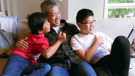 father and sons using digital tablet in living room 4k