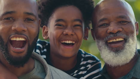 Portrait-Of-Loving-Multi-Generation-Male-Family-Standing-Outdoors-In-Garden-Park-Or-Countryside