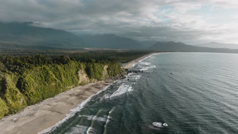 vista aérea de un vasto, dramático y remoto paisaje silvestre de árboles y montañas con el mar de tasmania en la bahía de bruce, sur de westland, nueva zelanda