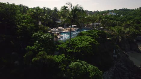 beach,-waves-and-ocean-top-view-in-slow-motion,-Huatulco,-Mexico,-aerial-drone-ascending,-zoom-out-to-beach-resort-with-swimming-pool