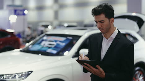 businessman writing notes at a car show