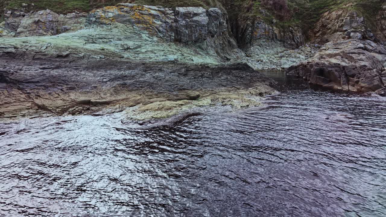 Aerial view of rocky coast reveals vibrant textures and colors