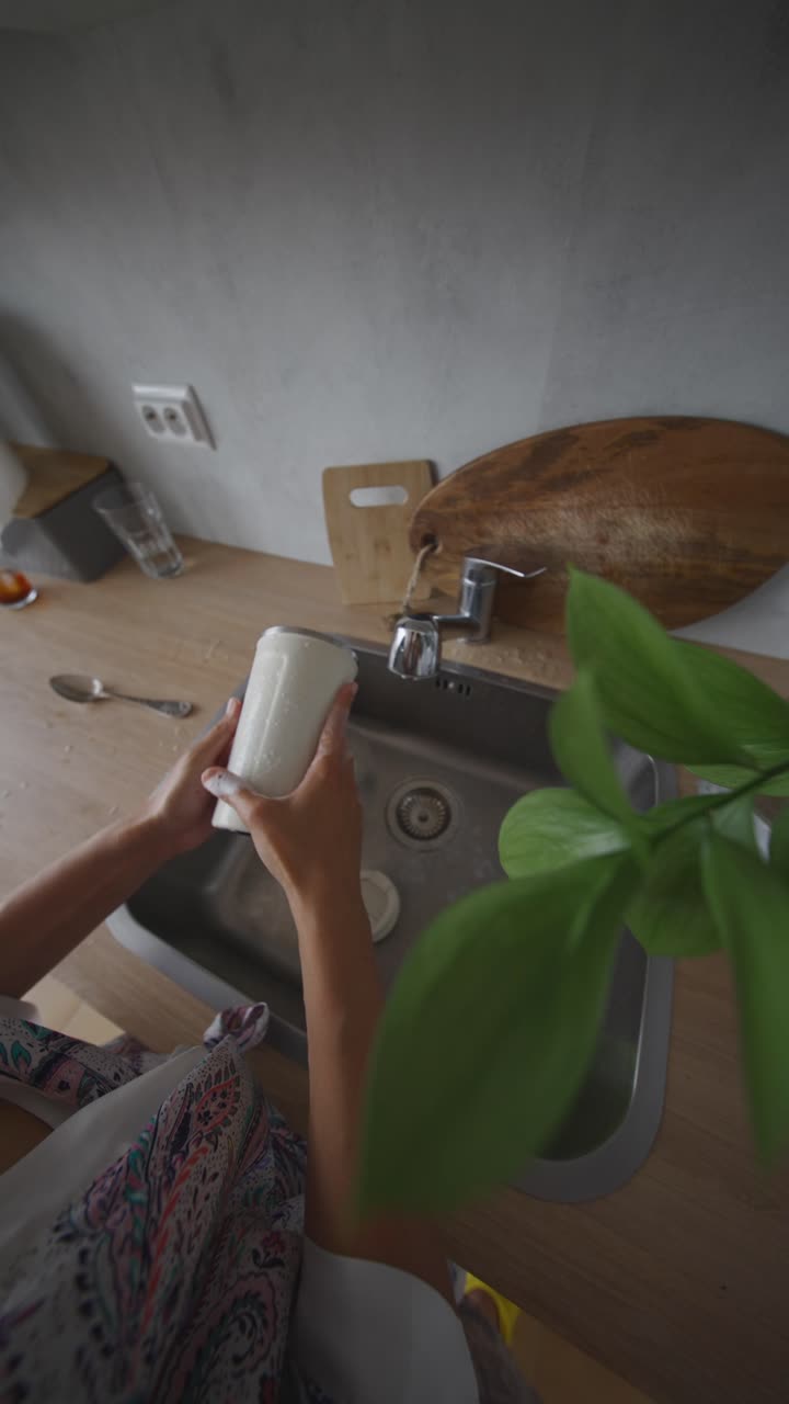 mujer lavando platos en el fregadero de la cocina