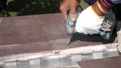 asian worker doing roof tiles installation, cutting, measuring process, close up