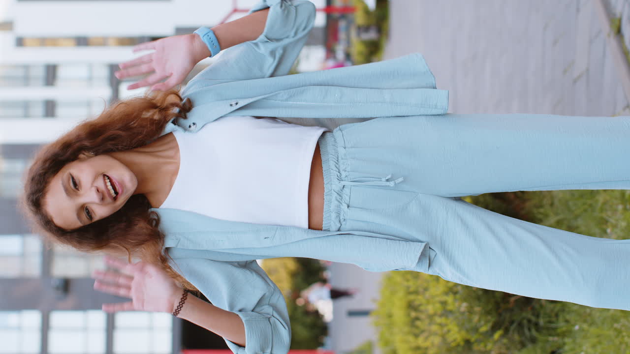 niña preadolescente sonriendo amistosamente a la cámara, agitando las manos hola, hola, saludo o adiós en la calle de la ciudad