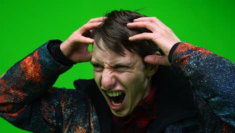 hombre sintiendo dolor de cabeza sosteniendo la cabeza con las manos en choque en el fondo de la pantalla verde. clave de croma