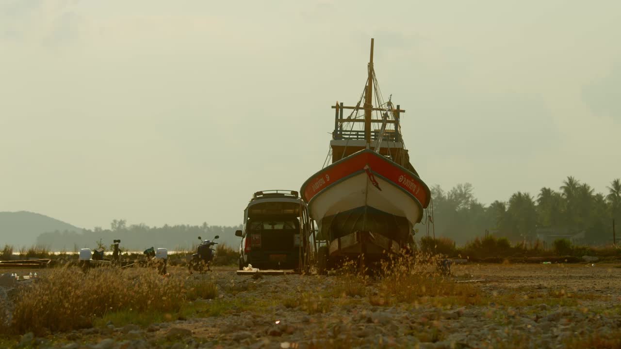Boat being transported by truck on a beach at sunset/sunrise