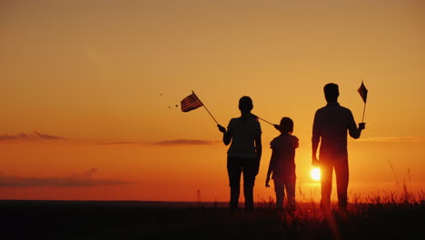 A-Group-Of-People-With-Flags-Of-America-Looks-At-The-Setting-Sun-Independence-Day-In-The-Usa