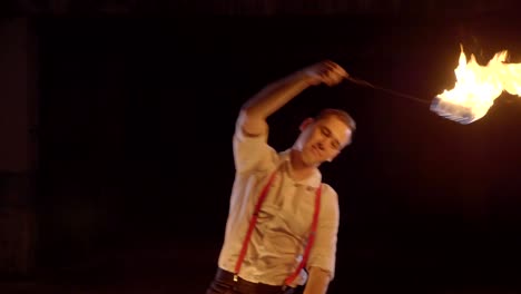 artista masculino realizando un espectáculo de fuego en la oscuridad en cámara lenta.