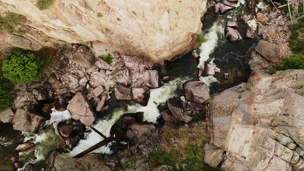 Drone footage descending onto a fast-flowing river cutting through a rocky canyon in the American West.
