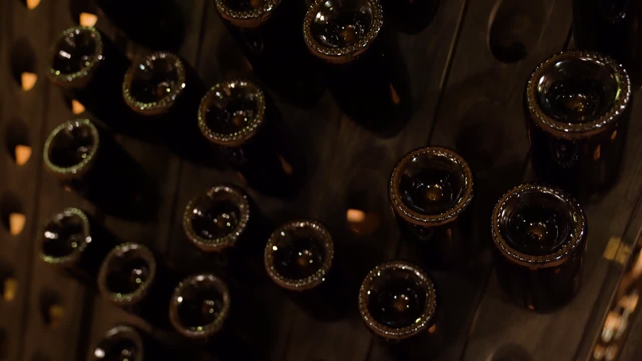 Close-up of upside down wine bottles in wooden rack in wine cellar