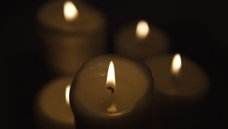 view of top, slide from right to left, burning candles occupy the whole area, composition on black background, take focusing from blurred, slow motion