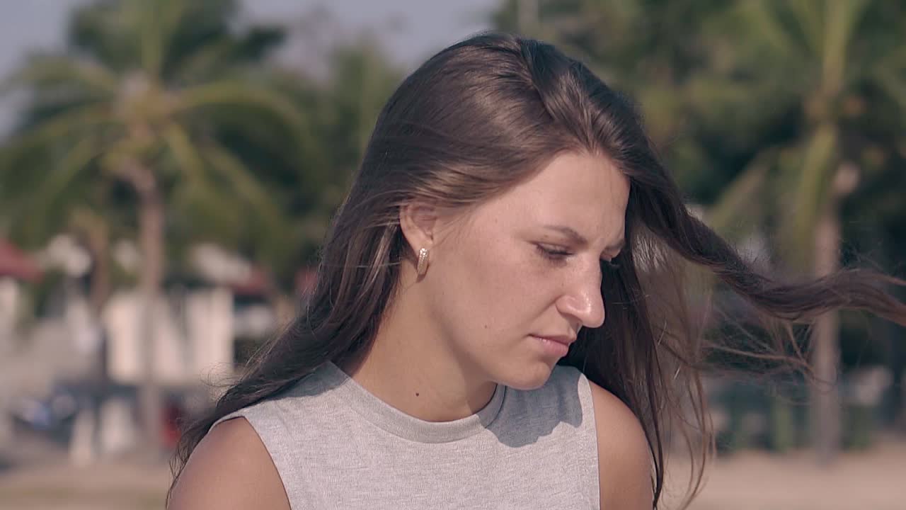 화가 난 젊은 여자가 열대 해변에서 느린 영상으로  ⁇ 고 있습니다.