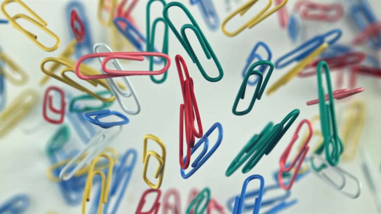 Livlige papirclips flyder og kommer i skarpt fokus.