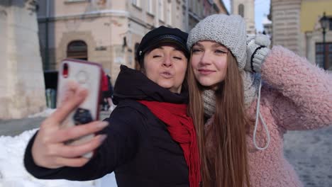 Two-young-smiling-women-tourists-bloggers-taking-selfie-photos-portrait,-video-conferencing-call