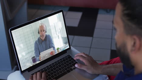 hombre de oriente medio teniendo una videollamada con un colega de oficina masculino senior en una computadora portátil