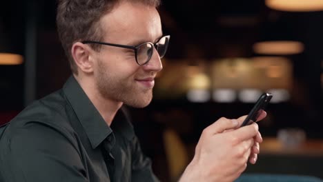 close-up portrait of a handsome curly man with a smartphone in his hands