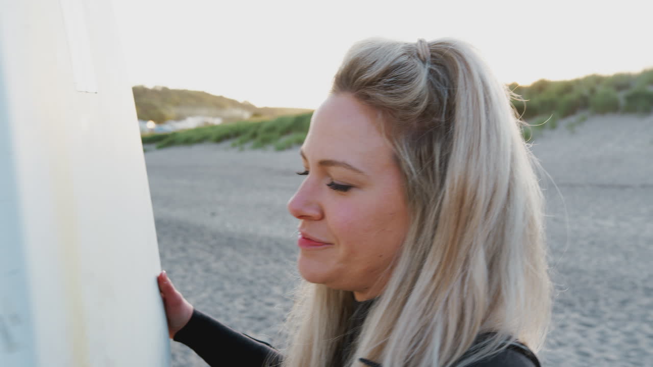 mujer con traje de neopreno sosteniendo una tabla de surf disfrutando de unas vacaciones de surf en la playa